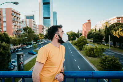 Young man standing against buildings in city