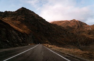 Road leading towards mountain against sky