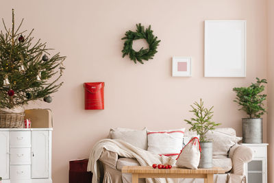 Stylish christmas living room interior with sofa, tree and wreath, mailbox, gifts and decorations