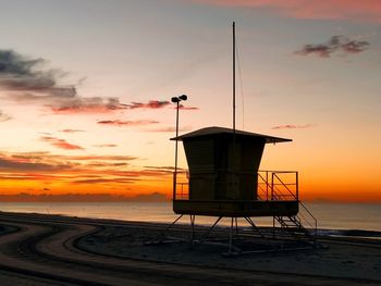 Lifeguard hut on beach against sky during sunset