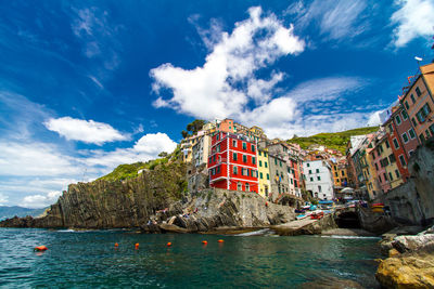 Buildings by sea against sky