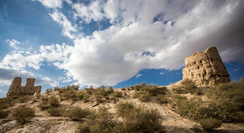 Rock formations on landscape against cloudy sky