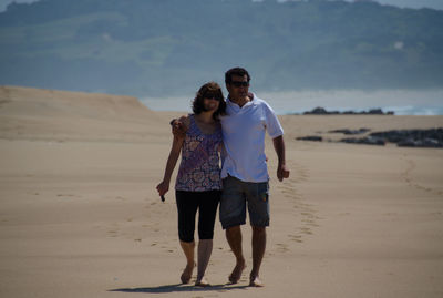 Smiling mid adult couple walking at sandy beach