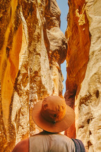 Young man wearing a hat, looking up and exploring a slot canyon in kanarra fall, utah.