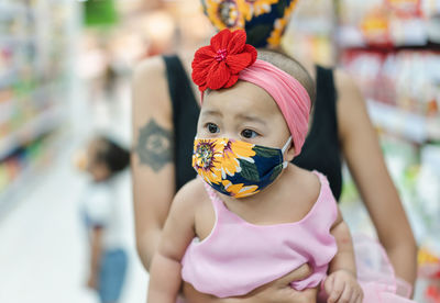 Mother carrying toddler with mask in supermarket