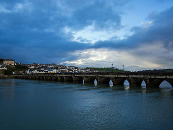 Arch bridge over river against sky in city