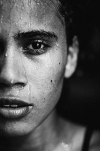 Close-up portrait of young woman against black background