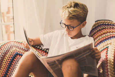 Boy reading newspaper while sitting at home