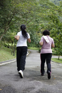 Friends running on footpath at park