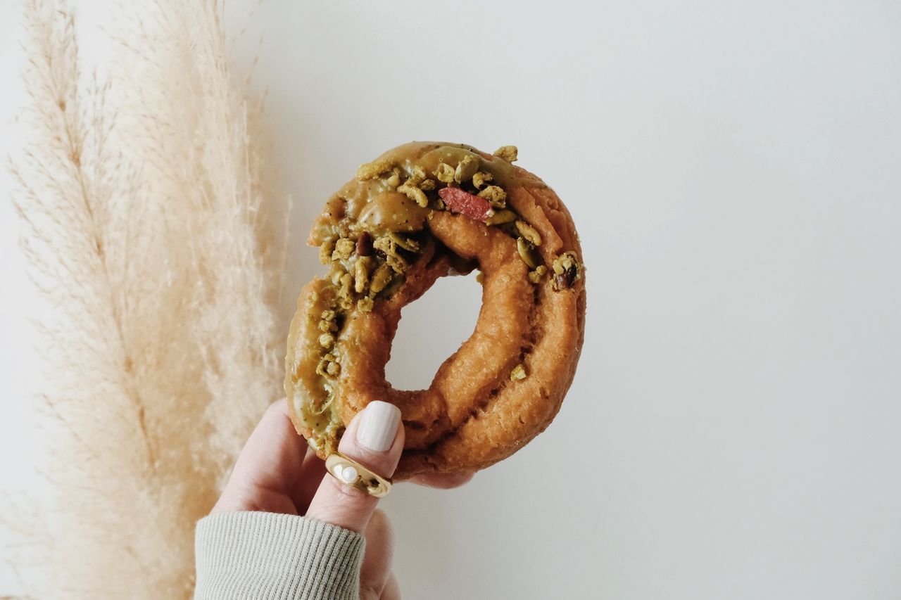 pretzel, hand, food and drink, food, one person, holding, snack, indoors, baked, studio shot, freshness, close-up, unhealthy eating, sweet food, clothing, bread, doughnut