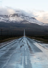 Road amidst snowcapped mountains against sky