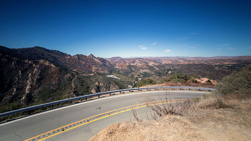 Road by mountains against clear blue sky