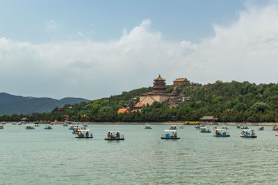 Boats in sea against cloudy sky