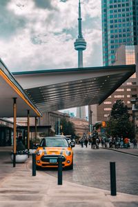 Cars on road by buildings against sky