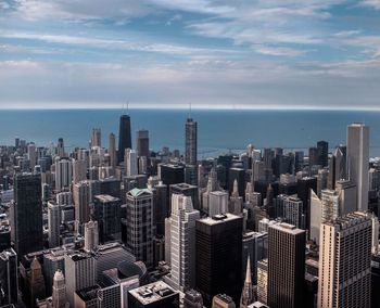 High angle view of cityscape by river against cloudy sky