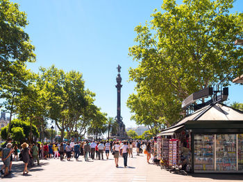 Group of people walking on street amidst trees in city