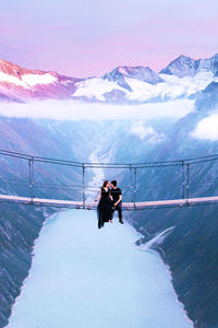 Woman standing on snow covered mountain against sky