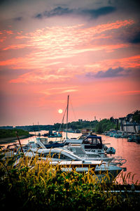 Boats moored at harbor during sunset