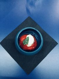 High angle view of fruit in plate against blue background