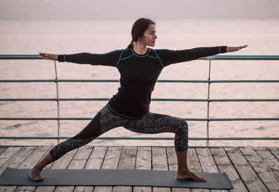 Full length of woman exercising on footbridge