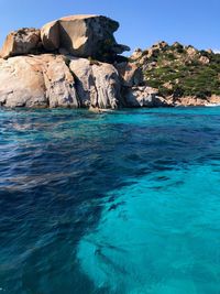 Rock formation in sea against blue sky