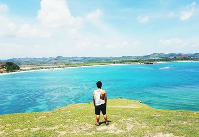 Rear view of man standing on beach against sky