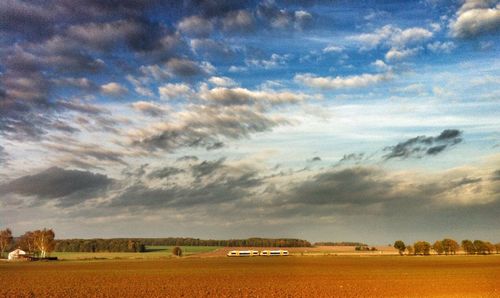 Scenic view of field against cloudy sky