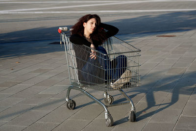 Portrait of woman sitting in shopping cart