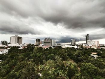 High angle view of trees and buildings against cloudy sky