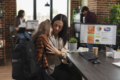 Businesswoman embracing with daughter at office