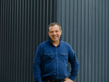Portrait of a smiling man standing against blue wall