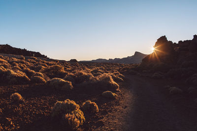 Scenic view of rocks against clear sky during sunset