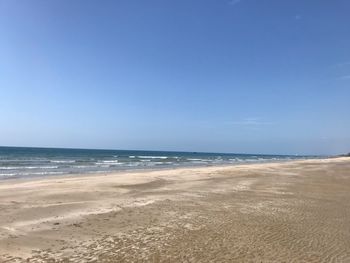 Scenic view of beach against blue sky