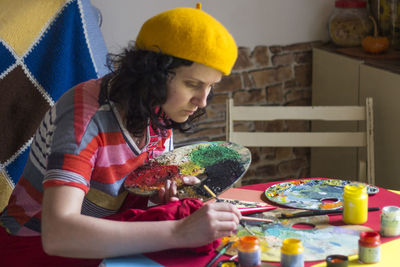 Midsection of woman holding umbrella while sitting on table at home