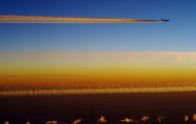 Scenic view of vapor trails in sky during sunset