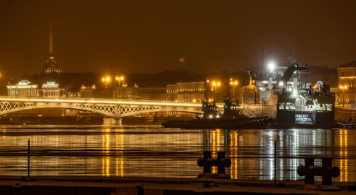 Illuminated bridge over river at night