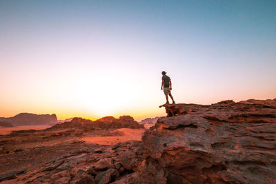 Man standing on rock at wadi rum against clear sky