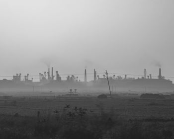 Panoramic view of factory on field against sky