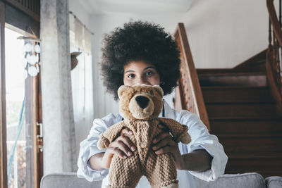 Portrait of doctor holding stuffed toy at home