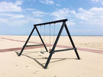 Swing on beach against sky