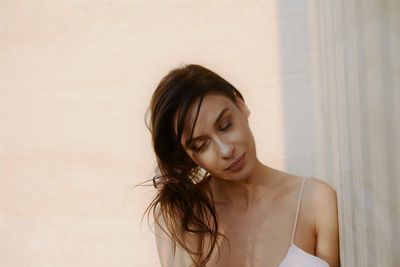 Portrait of beautiful young woman against wall