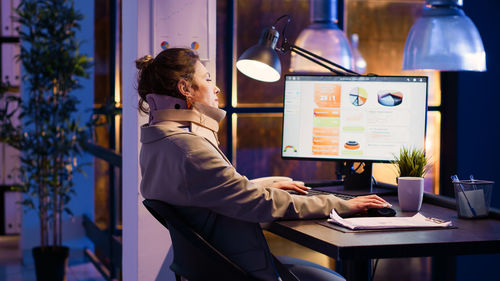 Side view of woman using laptop at office