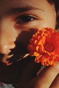 Close-up portrait of girl holding orange flower