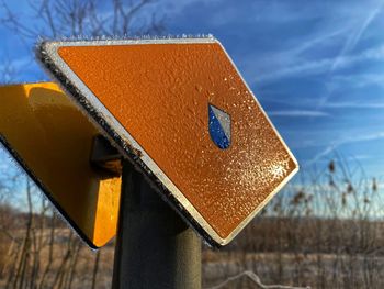 Close-up of yellow sign against blue sky