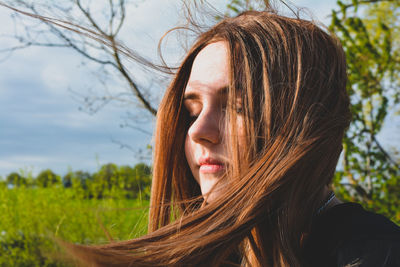 Close-up portrait of young woman. standing in the sun in the wind 