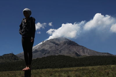 Full length of woman standing on wooden post over field against popocatepetl