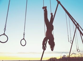 Man hanging upside down on outdoor gymnastic rings
