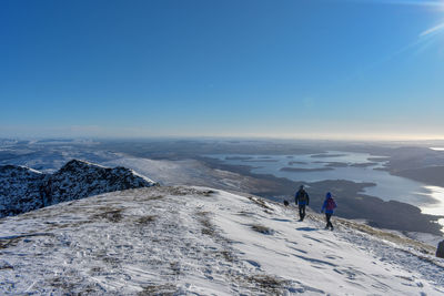 People on snowcapped mountain against sky during winter