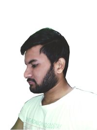 Portrait of young man looking away against white background