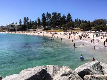 People enjoying at beach against clear sky